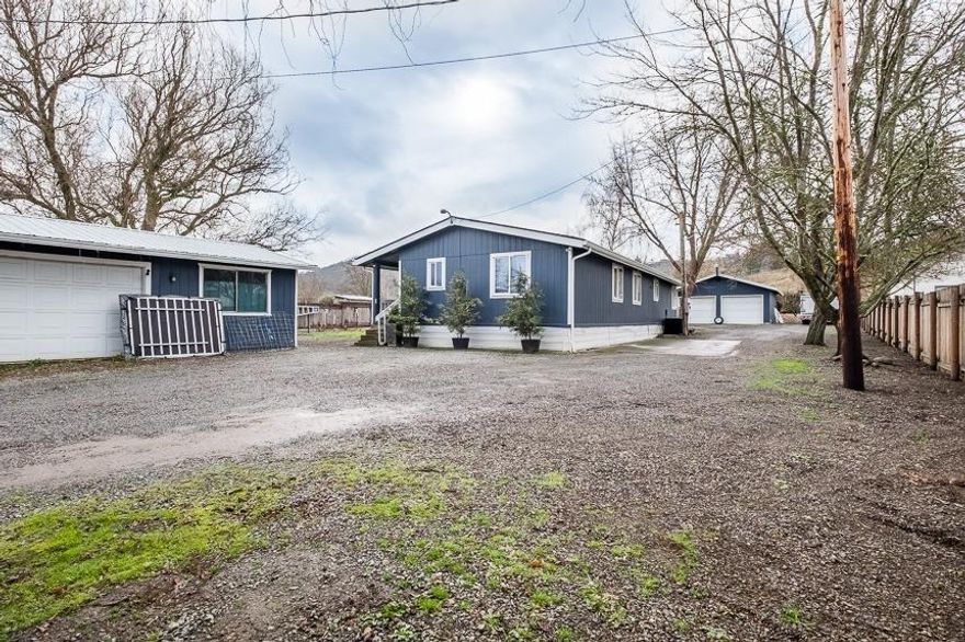 Located in SW Medford, you will find this 3 bed, 2 bath, 1,400 SQFT home on two tax lots with Irrigation from Medford Irrigation District. The entrance features a one of a kind automated gate and extra parking for RV's and more! In addition to the parking are 2 detached, finished garages with power. One garage has a workshop space with water, cabinets, countertops and a sink. Upon entering the home, you'll see new laminate flooring, 2 living rooms and a dining room with vaulted ceilings. The home has been well maintained and has new interior and exterior paint. The kitchen has stainless-steel appliances and the master suite is spacious, features a walk-in closet and private bathroom. Other notable features are the large yard and garden area adjacent to the irrigation canal just behind the property. The home also features a large deck with a hot tub. Call today to schedule your showing. Listing agent is related to seller.