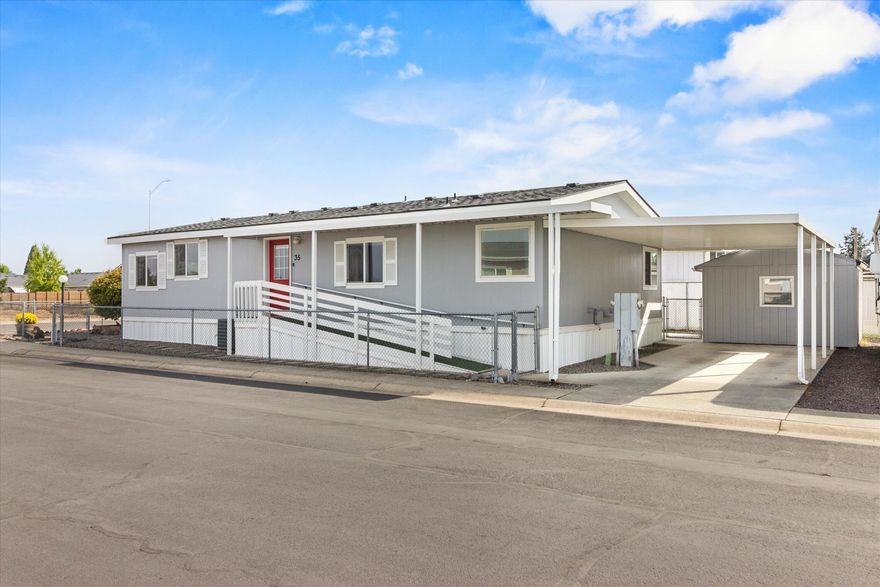 Back on the market—no fault of the property! Designed for ease of living, this 2-bedroom, 2-bath, 1,296 sq. ft. home features accessible ramps, step-free entry, and wide walkways—ideal for long-term comfort without the expense or hassle of retrofitting, The kitchen offers warm wood cabinetry, a breakfast bar, and ample storage. Enjoy a spacious living room, versatile den/office, and a primary suite with walk-in shower and soaking tub. Vaulted ceilings add an open, airy feel. Recent updates within last six years include roof, exterior paint, microwave, refrigerator, and water heater, providing peace of mind and built-in savings. Outside offers a low-maintenance yard, covered patio, 12x12 shed, carport, and RV parking. Combining affordability, accessibility, and thoughtful updates, this home is a great option for 55+ buyers seeking comfort, convenience, and lasting value.