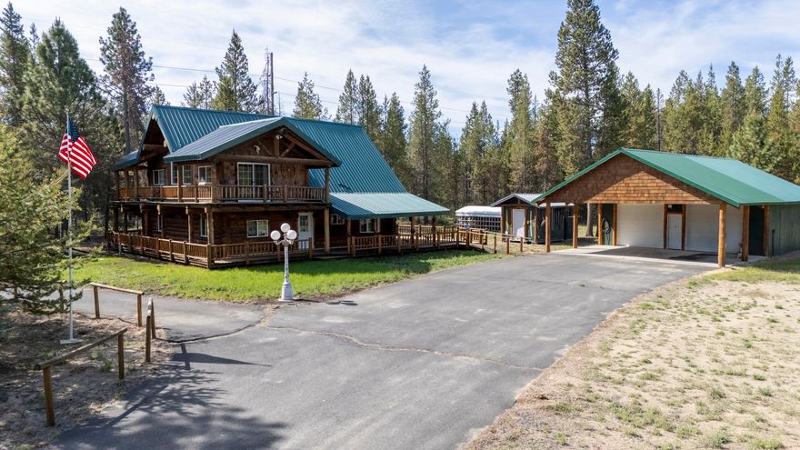 Bring in 2025 with a $5000 credit towards Buyers Closing Costs, good thru January 5, 2025. Discover the perfect blend of rustic charm and modern comfort in this beautiful log cabin built in 2002 with 1581 sq ft., on 7.61 acres. This impressive property features a wrap-around partially covered deck with an additional deck off the primary bedroom upstairs. The spacious Living Room features ample natural light through large windows and a stunning hearth for the certified wood stove.  A sliding door conveniently connects the kitchen and dining area to the deck, and an entry side door provides access to the laundry room. Additionally, the property includes a detached double car garage with attached carport, a workshop area and a covered carport. Don't miss the metal covered 24x30 RV Storage, Storage Building, along with the extra space for RV Parking, complete with electric and sewer hookup.