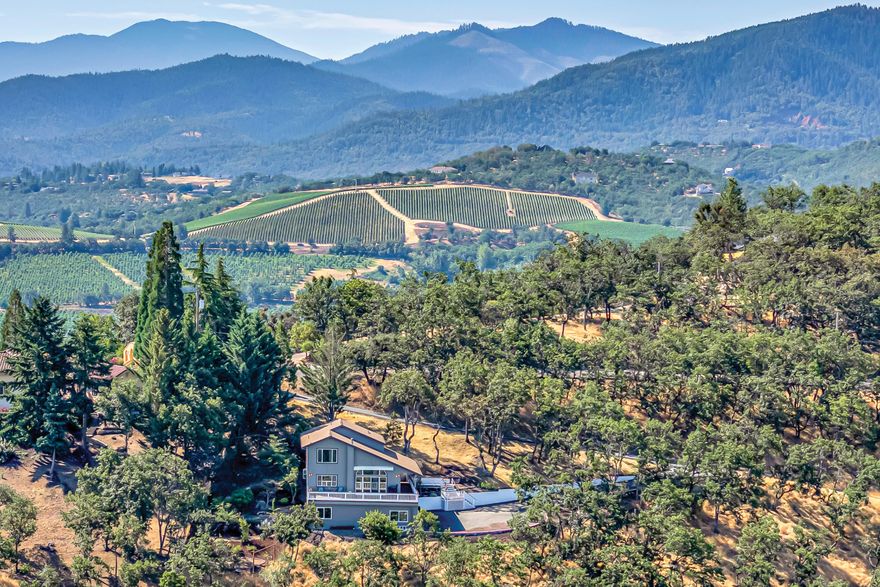 Stunning panoramic valley and mountain views from this private country home on serene landscaped acreage just outside the city limits of Jacksonville! New interior and exterior paint, upgraded HVAC and electrical, all new septic system, and new roof in the last eight years. Views from nearly every window, abundant natural light, open-concept great room with high vaulted ceiling, bamboo floors, restained cedar deck, kitchen with stainless appliances, dining area, guest bedroom, full guest bath, and laundry mud room on main level. Upper-level primary with treehouse-like views, renovated full ensuite bath with floating double vanity, large soaking tub, shower with glass surround, and guest bedroom or office with ensuite half-bath. Spacious lower-level family room or potential guest suite with gas fireplace, built-ins, wet bar, sliding glass doors, insulated garage with poured concrete slab, 220v circuit, and enclosed garden workshop with ample storage. Inquire for details!