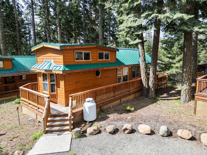 Escape to nature with this cozy and fully furnished mountain cabin nestled in the Hyatt Lake area, just a short drive from Ashland. Situated on over 30 serene acres, this 2007 cabin-style manufactured home offers year-round access, making it ideal as a private getaway or vacation rental. The 399 sq ft home features a rustic yet modern design with a main-level bedroom, full bathroom, and a spacious loft that comfortably sleeps up to four. Enjoy relaxing on the large deck with private spa, surrounded by trees and mountain views. The home is equipped with forced-air propane heat, community water, and a septic system for ease and comfort. Located within a managed community, HOA services include winter snow plowing and access to a new community gazebo and picnic area. Outdoor enthusiasts will appreciate the nearby lake access and hiking trails. Whether you're seeking a peaceful personal retreat or a turnkey short-term rental investment, this unique property offers it all. Come tour!