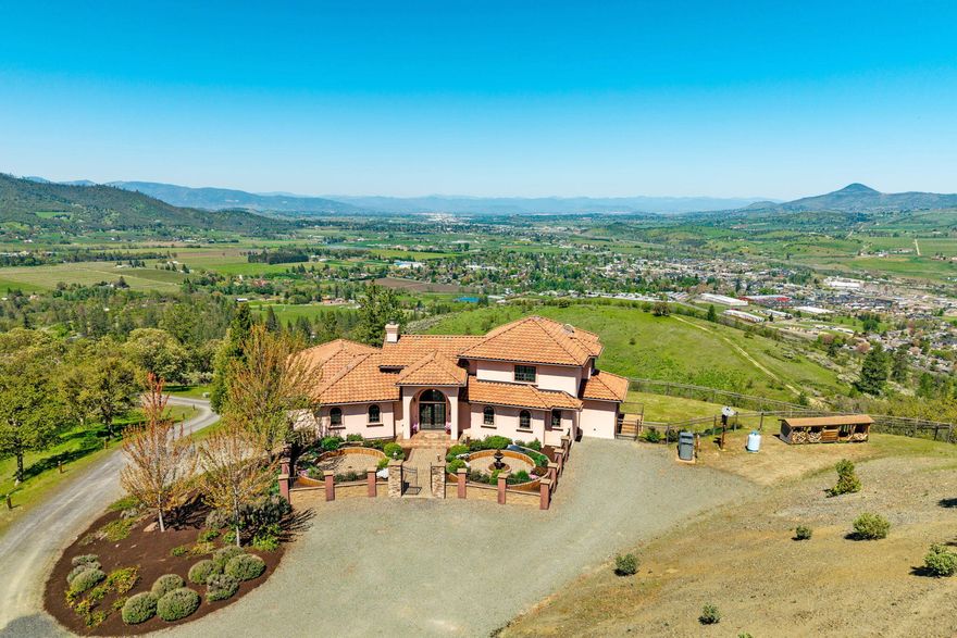 This may be the best view you will ever see! Astounding vistas stretch across the Rogue Valley, beyond the Table Rocks to the Western Cascades. Experience end of road privacy on this 25+ acre estate. This luxury residence presents an old world charm that is warm & inviting, designed for comfort & sophistication. The home features soaring beamed ceilings, stone fireplace, Ironwood cherry floors, walls of windows that extend to the expansive veranda with arched portals that frame the forever view. Large chef's kitchen with Viking Professional range, granite counters, large island & dining bar, formal & informal dining. Beautiful wood detailing features hemlock & knotty alder. Main level primary opens to veranda. 4 bedrooms, 4 baths, total of 4593 SF. Spacious art room/office plus large workshop. 3 car garage. Whether you're hosting gatherings or enjoying peaceful solitude, this home delivers with style, space & serenity -- all in a setting that captures the very best of high-end living.
