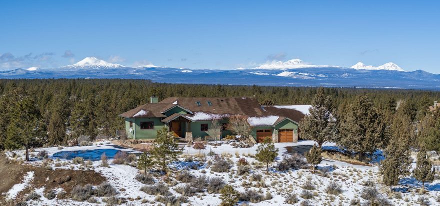 This home is a rare find in Bend with its panoramic views of the Cascade Mountains, Ochocos, and Paulinas. Sitting on stunning 20.14 acres and backing to the Deschutes National Forest, you'll have direct access to the trails for all your outdoor fun. This private home offers a 3 or 4 bed (office if desirable), 2.5ba, primary on main, office, large laundry, two family rooms, a living room with a wood fireplace, and custom upgrades throughout. Knotty alder doors, baseboard and trim, as well as custom cherry entertainment center and built-in display cases. Recently painted and with recent kitchen upgrade. Two newer heat pumps. Three car garage with  16 x 27ft attached shop addition with 220V outlets. Backyard is fenced, home has lovely water feature, a greenhouse, a paved driveway, in a paved area of Bend.