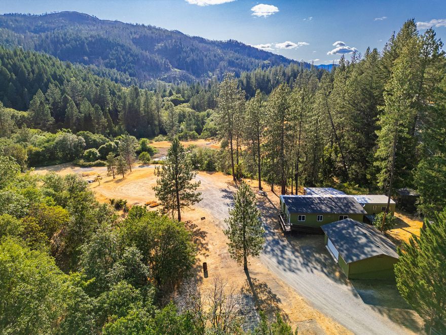 Opportunity in beautiful Merlin! Just 10 minutes to town and I-5, this peaceful property offers privacy, views, and utility. Enjoy a large detached shop/garage, connected water storage, & access to Jumpoff Joe Creek. Septic is installed and there are 3 wells (lower-producing—2 drill logs attached). The existing single-wide mobile is older & likely ready for removal, but it connects to a stick-built addition that includes a spacious family room, extra bedroom, & storage. Property extends to the middle of Jump Off Joe Creek.  There are three RV hookups.  This could be a head start on future plans. Whether you're looking to build new, bring in a replacement home, or simply enjoy the rural setting, this property offers infrastructure, flexibility, and room to create.