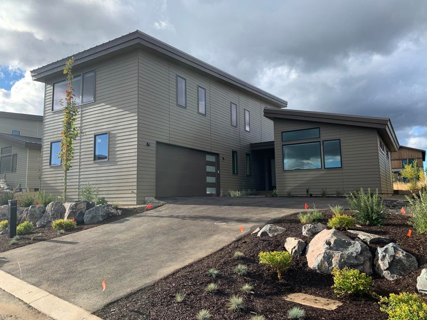 Introducing a new contemporary design by BendTrend Homes in the Trailhead community of Tetherow. This home features a 3,005 sf two-level floor plan with primary suite, mud/laundry and large den on the main level. There are two additional hybrid en-suite bedrooms and a bonus room upstairs. Luxury finishes and craftsmanship throughout include hardwoods, quartz counters, high-end JennAir appliances, fully tiled showers and floors in all bathrooms, stylish fixturing and Sonos system as standard. The homesite opens to an inviting common area green space. Direct access to Phil's Trail system for mountain biking and hiking just out your back door from this enclave of 28 homes across from the Tetherow pool, fitness center, dining, and golf course. Photos are of other completed homes. Buyers in the early phase of construction will be able to select many of their own interior finishes. Under construction with estimated completion - early Summer.