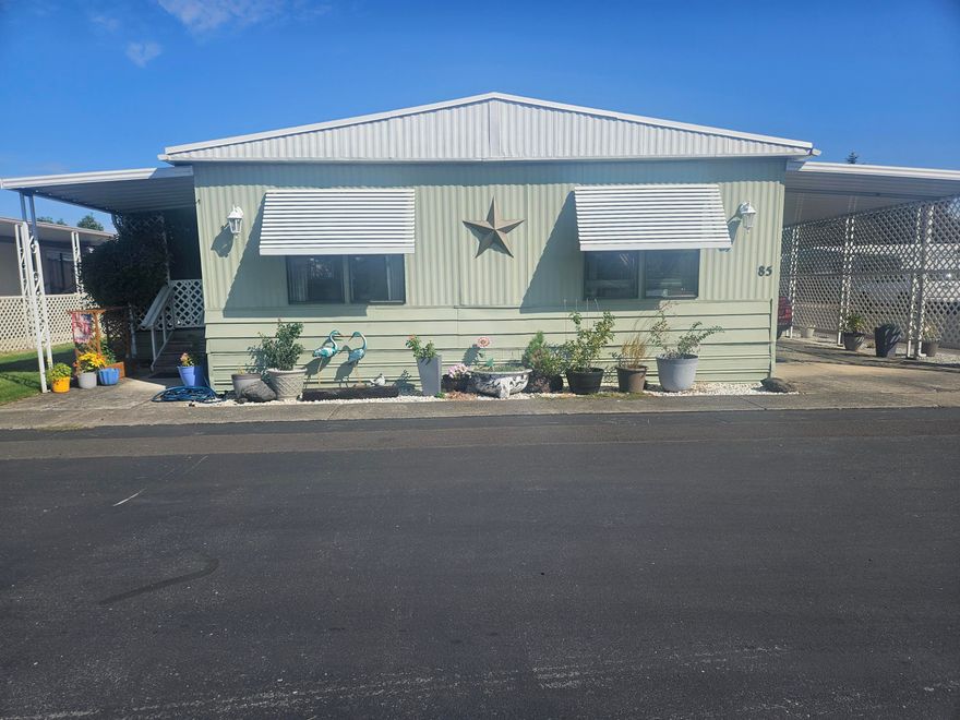 This 1742 sq. ft. manufactured home has 2 large bedrooms and 2 full bathrooms. The master bedroom has its own private bathroom 2 closets. One is a walk in closet. There are 2 family and dining room with a wet bar in between them. Office / utility room. The fenced area has sprinkler system. Private covered front porch and carport. 2 outbuildings, one is a workshop. New belly wrap and vapor barrier installed 2025. New kitchen flooring 2025. There is a community pool, hot tub, pool table, exercise room, and a community kitchen. They have holiday get togethers.