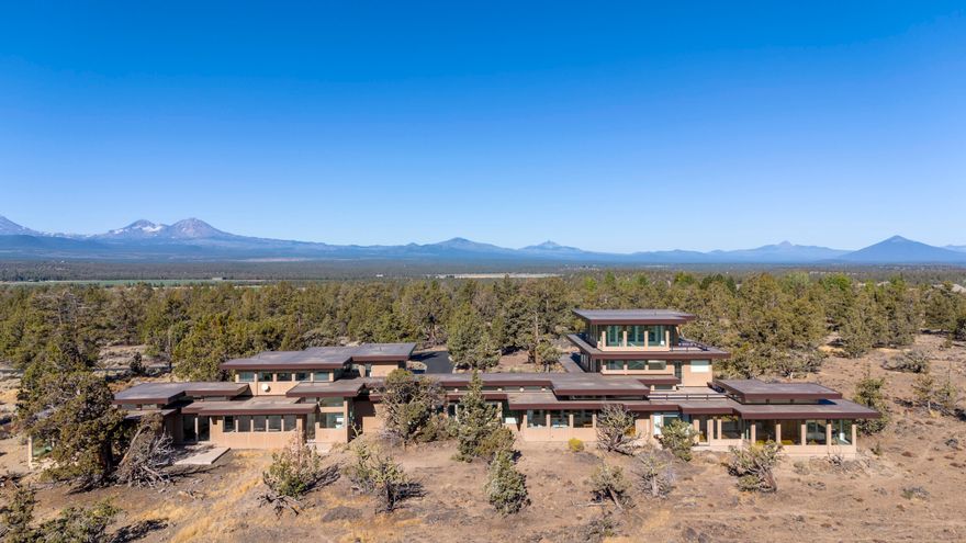 Spectacular one of a kind modern architectural masterpiece in a highly sought after Tumalo location! Privately perched on 11 acres in the midst of a historic Juniper Forest & epic rock outcropping. This glass palace offers unimpeded 360-degree panoramic views of all of Central Oregon's marvels. You'll enjoy the magical Powell Butte sunrises, breathtaking sunsets of the Cascade Mountains, & beautiful scenic landscapes. The well thought out structural design lends itself to multigenerational living separated by a massive soundproof hallway w/ towering ceiling. The floorplan is light & open featuring huge walls of windows, stunning views from nearly every room, 2 elegant kitchens w/top of the line appliances, 4 luxurious primary suites w/tiled showers, 6 private decks, 7 patios, a huge gym w/sauna, 4-car garage, private gated courtyard entry that's heated, beautiful oak flooring on main level, water feature pond, 4 efficient furnaces & water heaters, huge laundry room, & Butler's pantry!