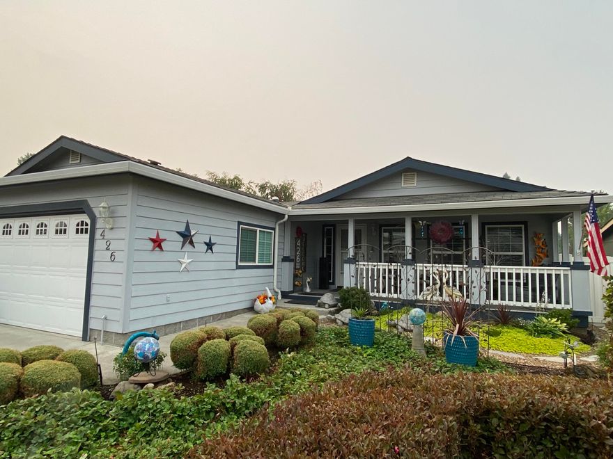 Wonderful 55 and over community! 3 bedroom, 2 bath triple wide modular home w/covered front and rear patio and attached 2 car garage. Spacious floor plan with living and dining areas, good sized kitchen, with custom cabinetry, crown molding, breakfast bar, glass top range/oven combo, micro hood, trash compactor and refrigerator, stainless sink w/instant hot water. Large master bedroom w/vaulted ceiling, ceiling fan, walk in closet, master bathroom double sinks, stand up shower and privacy toilet. Open living area w/vault, plant shelves, and ceiling fan. Rear covered porch/deck w/garden area, tomato plants and room for more fruit and veggies. Front/rear drip system on timer. Home has been well kept and cared for. New water heater in 2021, new toilets in 2019. HVAC recently serviced.