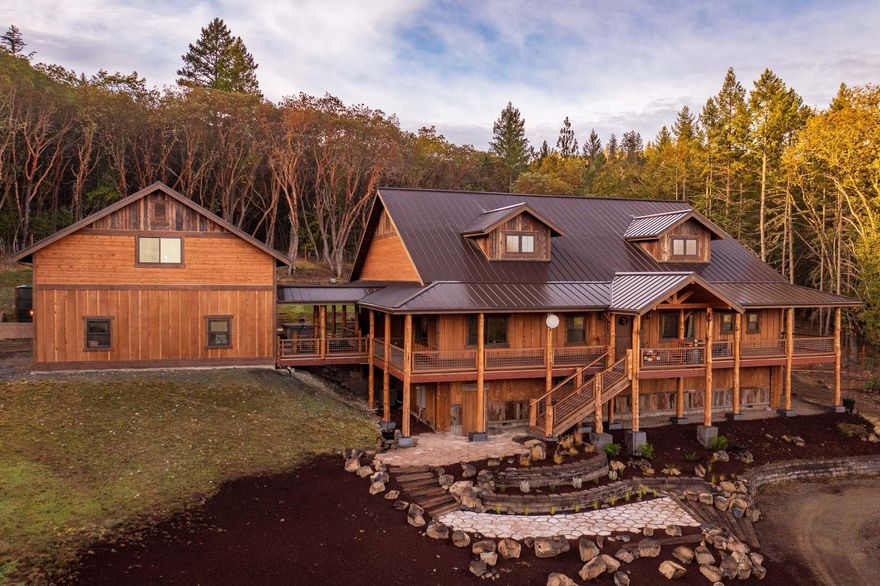 Tranquility awaits in this custom lodge home on 4.83 secluded acres with amazing views. This single level home features 2,688 sf of living space & 2,000+ sf of covered patio and deck. Custom rustic features throughout including wood beamed vaulted ceilings & reclaimed timber. The split floor plan centers around a fabulous great room w/fireplace & a beautiful open concept kitchen. A true chef's delight with dual refrigerators, dishwashers, & ovens, plus great storage & counter space. The flow is seamless to the expansive outdoor space & peaceful backyard. The master suite enjoys vaulted ceilings, large walk-in closet, & custom oversized shower. 2nd bedroom suite w/hammered copper tub & custom vanity. Two more bedrooms w/walk-in closets share a Jack & Jill bath. The 3-car garage is 1,260 sf plus a 670 sf 2nd story that has a full guest quarters & 16x20 storage room. A massive daylight basement storage space, garden w/greenhouse, hot tub, fire pit, & waterfall round out this offering.