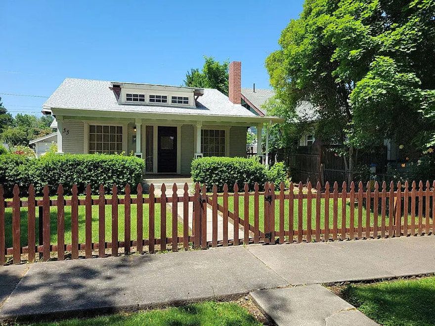 Set behind a classic picket fence, this two-bedroom home offers a well-planned layout with an upstairs bonus room and half bath that adds meaningful flexibility for guests, creative work, or a private office. The main level feels calm and welcoming, with wood floors, built ins around the fireplace, and natural light that softens each room. The dining area flows into a vintage style kitchen with ample cabinetry, tile accents, and the kind of original character that is increasingly hard to find. Both bedrooms are comfortably sized, and the main bath features period tilework and a traditional tub shower. Upstairs feels unexpectedly bright and open, offering a secluded retreat with its own half bath and wide window views. The backyard is designed for ease, with a courtyard style setting that appeals to both tenants and owners for its low maintenance feel. A detached outbuilding gives added storage or hobby space, creating a balanced property with long term potential.