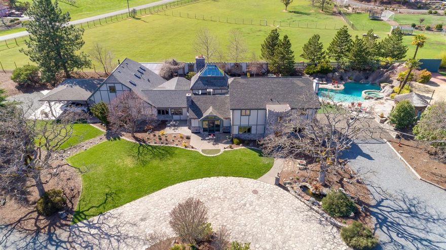 One of a kind 5856 SqFt Country Estate on 4.78 acres made for entertaining & outdoor living! Just outside of Jacksonville, this western foothills property features views of Roxy Ann & Mt Mcloughlin to the east amidst sweeping panoramic views of the Rogue Valley. The custom main home has 3 BR's & 4 BA's, exquisite open chef's kitchen with Wolf & Viking appliances, granite counters, butcher block island, fireplace w/pizza oven, pantry, counter seating, living room w/fireplace, bar w/seating, 900+ SqFt game room, library/study, slate tile, hardwood floors, built-ins and 400 amp upgraded power. A private wing ADU w/separate entry has a full kitchen, bathroom, bedroom & living room. Venture outside to enjoy the resort style oasis pool w/waterfalls, slide, spa, custom rock & concrete work, Tiki Hut bar, bathroom, fountains, sand volleyball court, putting green, basketball court, handball court, in-ground trampolines & dirt bike track. A separate 4k+ SqFt garage w/200 amp power has RV parking