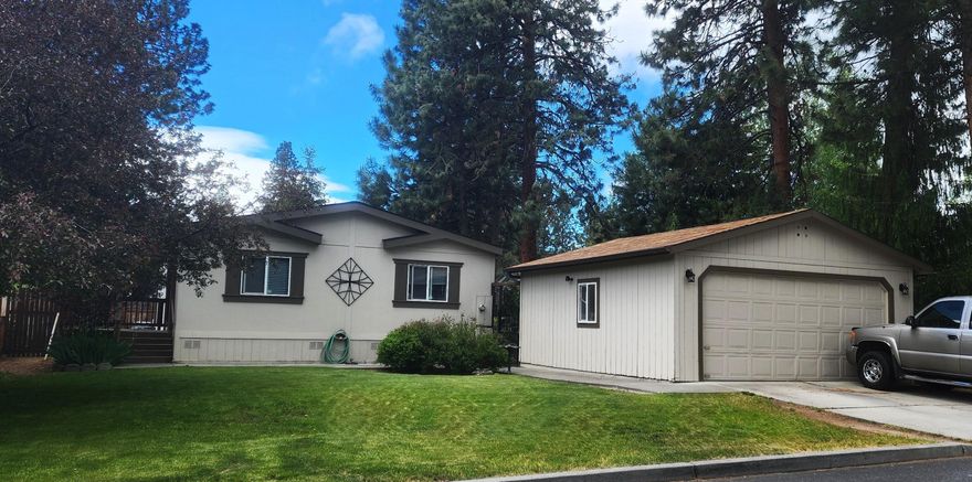 Cute, well-cared for home in Fox Hills family park in Bend.  Efficient, open floor plan with vaulted ceilings and wood laminate floors.  Spacious kitchen with lots of counter space, island with breakfast bar, SS range/refrigerator, and pantry.  Separate laundry room is connected to primary bathroom. Large primary bedroom has good separation from additional two bedrooms. Walk-in shower in primary bathroom. Central A/C.   Enjoy morning coffee on your front or back covered deck. Private, fenced back yard. Detached two car garage. Quiet neighborhood. Space rent is $886.73               and includes water, sewer, clubhouse, and street snow removal.  Home sold AS-IS. Come check out this terrific home!