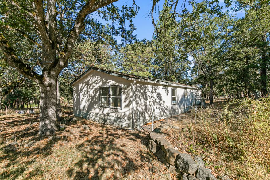 Imagine the potential of this picturesque, lightly wooded property, with its gentle slope creating a perfect setting for your vision. The parcel includes a spacious 32x48 workshop, built in 2009 with 10-foot ceilings, ready for your projects. While the 1997 manufactured home needs renovation, it offers an outstanding chance to customize your dream living space or start fresh with a new build. Great well and water quality. Picture yourself enjoying scenic vineyard views and the charming atmosphere of historic Jacksonville, just a short distance away. This property is being sold ''as-is''. Priced to sell.
