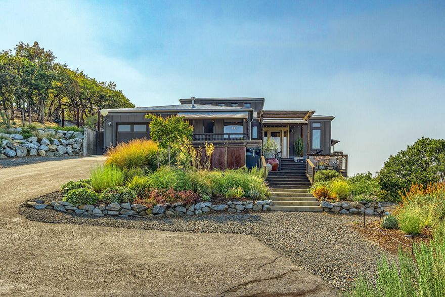 If you have amazing artwork, you may be tempted not to hang it, because each window of this home reveals the most magnificent of views of the Rogue Valley. Rolling hills, stunning sunsets and sunrises, vineyards, orchards you name it, you can see it. This beautiful home is 3080 sqft of single level living with well appointed kitchen and custom finishes everywhere that exude the luxury you would expect from any home placed on a knoll top like this home. Australian Hardwood floors cover most of the floors, except the kitchen and eating areas where there is a gorgeous tile. Two gas fireplaces, chefs kitchen, soaring ceilings over the dining area, tons of natural light flooding throughout the home and so much more, you must see it to appreciate it. a total of 34,000 gallons of holding tanks filled with rainwater from the metal roof, ensure irrigation for the garden and additional fire protection if needed. Huge storage in the walk in basement. Please see additional amenities list.