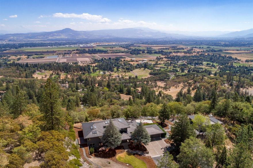 One of a kind, contemporary designed home displaying breathtaking views of the valley. Situated in a hilltop setting, blanketed with Madrone trees, this stunner has absolute privacy behind an automatic wrought iron gate. This modern style home has been updated with new furnaces, fresh paint inside and out, beautiful new hand-scraped Acacia hardwood floors, tile, and new carpeting in 2017. Fantastic floor plan with vaulted ceilings and double-sided gas fireplace. Gourmet kitchen is perfect for entertaining and includes 60 in Viking gas range, wine fridge, huge island, and plenty of beautiful cabinetry. 10,000 sf RV pad located at the bottom of property allows for easy storage for all your toys. Paved driveway leads to detached two car shop/garage w/oil pit, hoist, office and full bath. Two storage units, green house, built-in oversized hot tub, and a lifetime copper roof on all buildings.