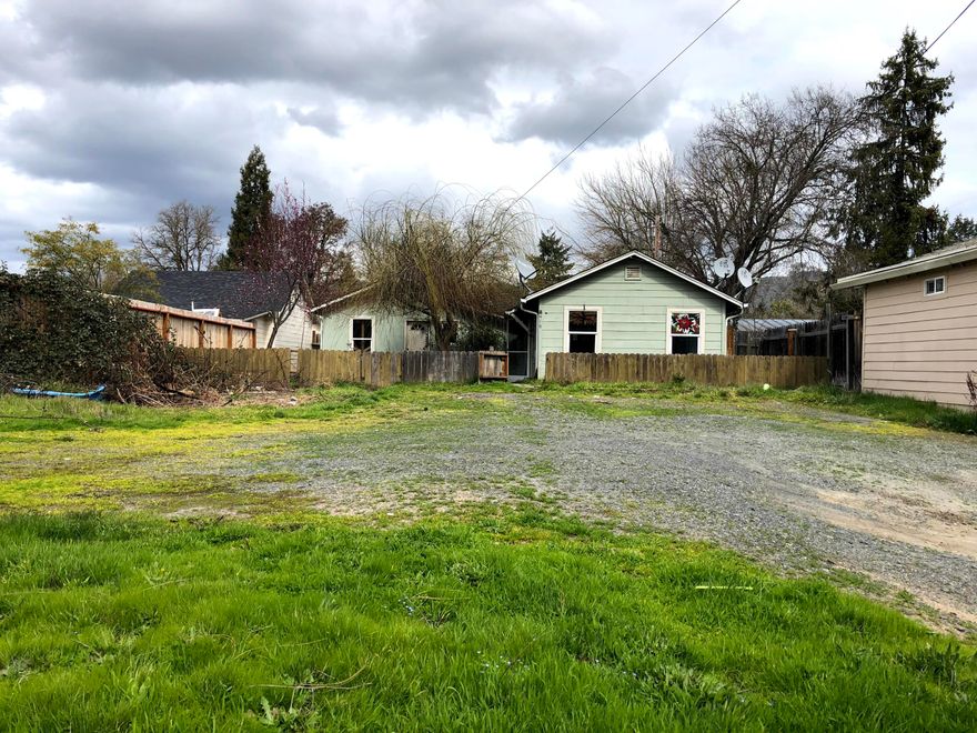 Calling all investors! This property boasts a convenient location close to downtown Grants Pass. The dwelling has two separate entrances for a possible mother-in-law setup. The open front yard is a blank slate, ready for an expanded build, ADU, or outbuilding. Alley access along the back of the property. Buyer to perform their own due diligence into any desired uses for the property. Sale is as-is, cash only.