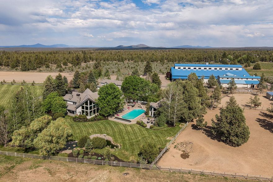 Owner will carry! Stunning 25.12-acre estate with unobstructed Cascade Mountain views and 11 acres of irrigation. The impressive 9,075 sqft 4-car garage home, offers 6 bedrooms, 6.5 bath and showcases granite kitchen counters, hardwood floors, and a soaring 30' VG cedar ceiling. Main-level primary suite includes a see-thru fireplace, spa-like bath with jetted tub. Features include a library, office, game room, guest suite, and a guest/staff apartment with a kitchen, bath, and laundry. Smart Lutron lighting/music, 9 heat pumps, zone-controlled heating, gourmet kitchen with Dacor stove and Subzero fridge. Enjoy the 990± sqft pool house with bathrm, steam shower, and sauna. Relax at the outdoor pool with slide, hot tub, and nearby Finnish sweat shed. Massive 26,539 sqft indoor arena perfect for motocross or horses, with stalls, tack rooms, paddocks, kitchen, full bath, and loft with viewing room. Gated property includes 375 spruce trees, fenced/cross-fenced, pasture, and two RV hookups.