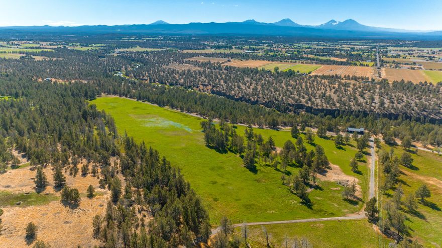 A sweeping view of Cascade peaks, the rush of the mighty Deschutes, broad pastures that give way to native pine and juniper groves, all are here. All will speak to your inner wild of peace and privacy, harmony and home. With more than 80 acres, you'll find room to roam, bluffs to hike, river banks and swimming holes to explore, and everywhere, space to breathe. This one-of-a-kind property includes a unique opportunity for a new custom build site, perched along the river rim with westerly views of sunsets and mountains. Historically this has been a working farm and ranch, with 66 acres of Swalley irrigation rights, 12 pastures, multiple ponds, machine sheds, a shop, hay barn, corrals and equipment to make it all hum. The original homestead, built in 1955 has 1,100 square feet with 2 bedroom, 1 bathroom and back porch views of the Cascade mountains and orchard. A rare opportunity for the creation of your private legacy estate amidst the beauty of an unspoiled section of Central Oregon.