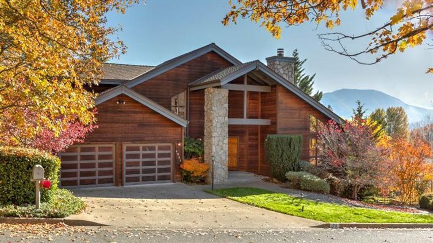 Stunning custom in this NW Grants Pass neighborhood features Redwood lap siding, gorgeous views from an expansive deck and over a quarter acre of meticulously landscaped grounds. Formal entry with etched glass windows opens into vaulted ceilinged living room with rock-faced gas log fireplace. All windows and sliding doors are oak trimmed, including the bay window. There are 3BR/2BA plus the sellers' favorite spot...a sunroom that is lined in knotty-pine and wall-to-wall windows that open onto the treetops. Other features of the home include a central vac system, plenty of counterspace in the kitchen, lots of storage in the laundry room as well as a built ironing board. Outside stairs lead from the deck which overlook a corner of the yard bursting with blooms. A white dogwood graces the front of the house, and in back a lovely water feature bubbles near the 12x12 greenhouse with electricity and water. Mature landscaping creates a shady haven from the world.