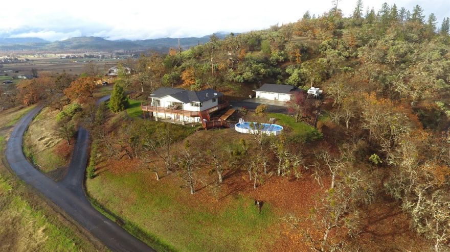 Spectacular views from Mt. McLoughlin, to west mountains and Table Rocks between! Situated on a small hill facing south, the 2613 sf home has 4 bedrooms, 3 full baths, office, family room in the daylight basement, and an open great room with living room, dining and kitchen opening out to over 1600 sf of cedar deck. The huge deck almost wraps the house and includes a BBQ deck overlooking the new semi-above ground pool. The 3-car garage is complimented with areas to park RVs or other toys. If gardening is your hobby, a 40' x 60' fenced garden, complete with timed drip system and raised beds of garlic, asparagus and artichokes already growing for you. Recent remodeling includes new roof, pump on private well, electrical panel, furnace, heat pump, interior and exterior paint, S/S appliances, carpet and bamboo flooring, and a huge deck. Don't miss this million dollar view for half the price!