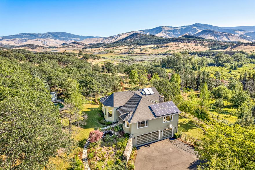 Spacious custom view home on acreage with swimming pool and mature landscaping near Emigrant Lake — just 8 miles from downtown Ashland! Main level with solid oak floors and fir doors, double-paned casement windows, vaulted living room with stone fireplace surround, parlor sitting room or office, formal dining with sliding glass door to balcony, kitchen with granite counters and island, informal dining or breakfast nook with gas fireplace, composite deck with BBQ hookup, half-bath, laundry room, primary bedroom with deck access, and full ensuite bathroom with radiant-heated marble floors, two closets, double vanity, soaking tub, and shower. Curved staircase to lower level with wet bar, two spacious bedrooms, full guest bathroom, and three-car garage with workshop. TID rights with sprinkler and drip irrigation, 2-kW solar array, oak and fruit trees, greenhouse, ~950 SqFt fenced garden, koi pond, and approximately one fully-fenced acre around the home. Inquire with agents for details!