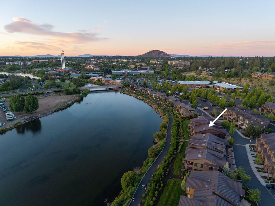 Nestled directly on the iconic Deschutes River Trail, this charming Deschutes Landing Townhome, is a one-of-a-kind offering! Overlooking the Deschutes River & Cascade Mountains in the distance the home is a rare blend of tranquility, modern elegance & unbeatable location. With direct access to all the best attractions in Bend's vibrant Old Mill District, this home is Being Sold Furnished, and invites you into a lifestyle of comfort, convenience, and natural beauty. From the moment you step inside, you'll be struck by the home's striking design, an artful blend of contemporary luxury and timeless charm. Thoughtful architectural details like exposed brick accents, movie theater, crestron system, sophisticated lighting, & 2 elegant fireplaces in both of the living spaces creates a warm and inviting atmosphere. Rich textures, quality finishes, and upscale furnishings throughout give the home a curated, high-end and move-in ready & turnkey home where the location means everything!