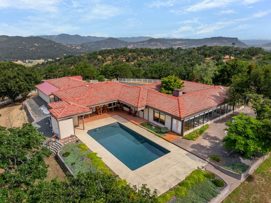 Mid-century modern elegance perched atop 20.36 private acres with breathtaking mountain and valley views!This stunning 4-bedroom,4-bath home features clean architectural lines,a unique indoor atrium that brings the outdoors in.The spacious kitchen has upgraded Thermador appliances and a view of the patio and pool so you don't miss the fun while cooking! The open living area is perfect for entertaining, flowing seamlessly to an incredible outdoor space with an inground pool, outdoor kitchen and spacious patio-deck. The luxurious primary suite offers a jetted tub, walk-in stone shower, dual vanities and a generous walk-in closet. The 1424 SqFt,  3 car finished garage with 3 phase power and added separate storage space will meet all  your storage and car needs.  With abundant RV parking and ultimate privacy, this one-of-a-kind property blends sophistication,comfort and natural beauty-your own mountain-top retreat awaits!