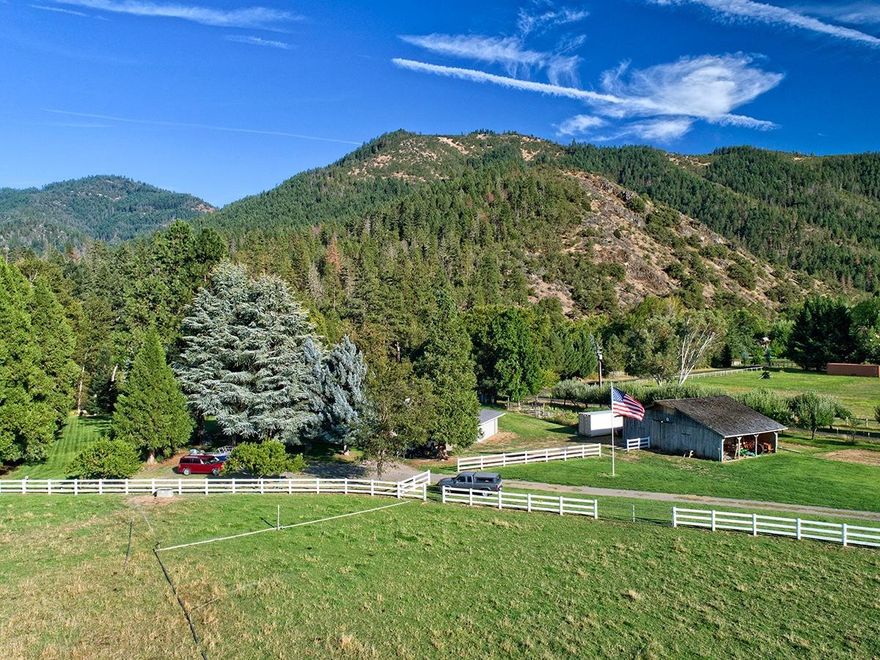 A rare opportunity awaits located just outside of Jacksonville, OR. This is the first time that this amazing piece of irrigated farm land has been on the market in over 40 years. With over 745' of Applegate River frontage this fully irrigated property is a blank canvas with incredible sun exposure. There are 3 separate tax lots fenced and cross fenced with irrigation risers throughout. As you enter the automatic gate and approach, you are greeted by a fully functional barn and a 2 car garage attached via breezeway to the home that offers a generous 2776 square feet. There is even an auxiliary detached 2 car garage behind the home. The home is 4 bedrooms and 2 full bathrooms + an office with a gourmet kitchen, expansive dining room and oversize living spaces. Offering new exterior paint, a new roof, newer furnace, this home is move in ready! There is a wonderful garden - including a mini vineyard and several mature fruit trees.