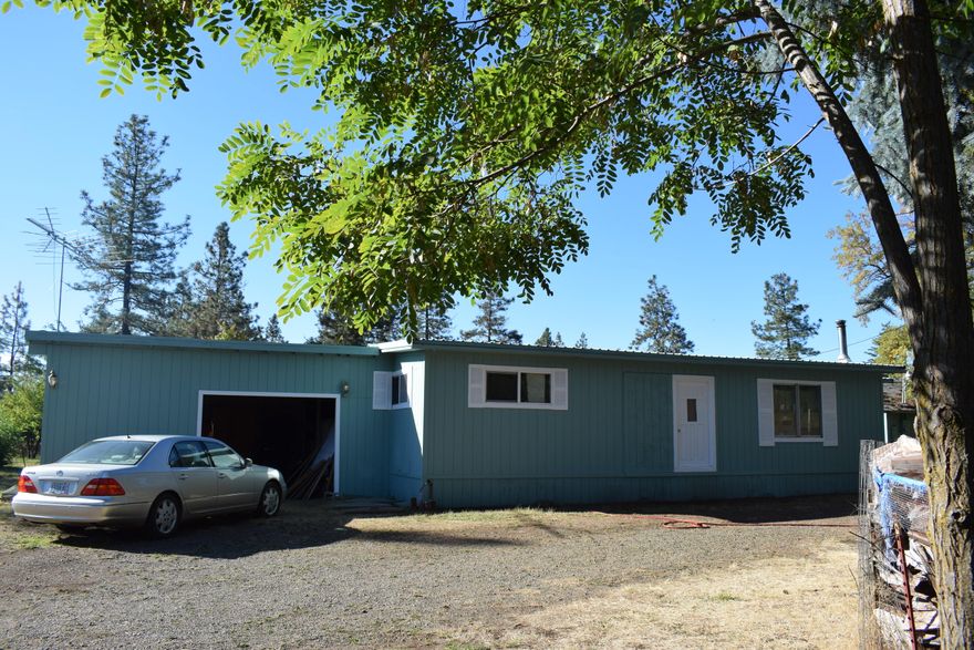 Embrace the joys of homeownership as you live on this level, over-an-acre piece of land with great views of the surrounding mountains. There are two living spaces on the property, one is an older manufactured home, freshly painted and roof recently resealed, with a large covered deck off the back and a carport built to one side. The other is an RV that sits under a well-built 20''x40' pole barn with additional rooms added on. Numerous mature fruit trees, grapes and ornamental plants adorn the property and there are two strong wells that supply water. One well rests inside a 12'x20' outbuilding providing plenty of extra room for storage. This property is being sold ''As Is''. With a little love, you can be living comfortably on a great piece of land with views, privacy, your own food established, plenty of water and room for others to stay...all for under 200K!!!  Seller is motivated!