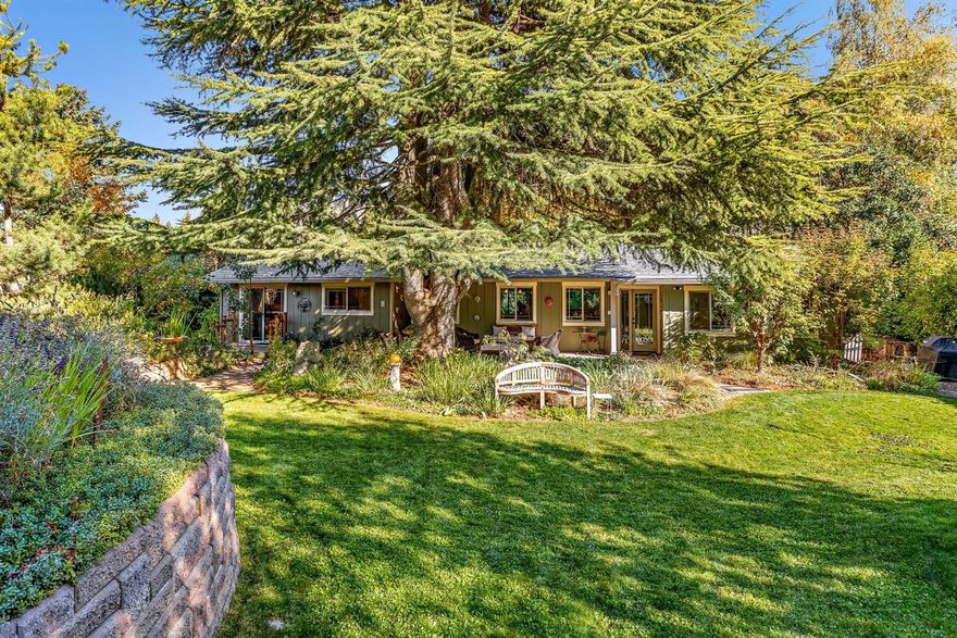 Single-level mid-century modern home, tastefully renovated with unique artistic details. Sited on a stunning private landscaped and irrigated acre, sanctuary-like grounds have been lovingly cultivated by master gardeners with rare and collectible plant species, custom stained concrete pathways, koi pond, extensive terracing, raised vegetable beds, and covered hot tub with composite decking. Interior features tri-stranded horizontal bamboo flooring, double-paned windows, designer LED lighting, operable Velux skylight, certified wood burning cast iron soapstone fireplace with honed granite hearth, and solid core doors. Kitchen equipped with quartz counters, stainless appliances and undermount sink, reverse-osmosis water filtration, and custom cherry full-extension soft-close cabinetry. Master suite outfitted with large closets, sitting area, sliding glass door to backyard, and tranquil bath with radiant heated tile floors and spacious rainfall shower with natural stone floor.