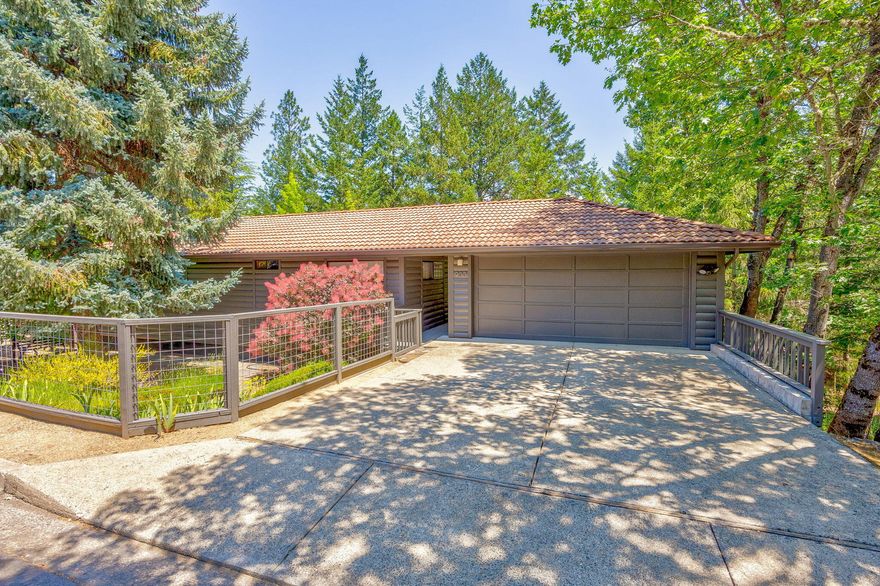 Charming artist retreat sits in a desirable forested setting above SOU campus on a level street at the City's edge.  Multiple decks overlook the TID canal for an added opportunity to enjoy the outdoors.  The home and 2-car garage have log siding and a tiled roof, and are well positioned for privacy.  The primary suite and second bedroom/bath are found on the main living level, along with laundry, kitchen and great room.  The lower level with it's own outside entrance contains another bedroom, bath, bonus/flex room and large storage room that offers many possibilities.  Vaulted wood ceiling in great room and well-placed windows provide for good natural light.  The updated galley kitchen with solid surface counters has been opened to the great room and embraces the overall contemporary flavor of the property.  Central heating/cooling on main level, baseboard on lower level.  No CC&Rs, no HOA.  Nature is at your front door with TID trail nearby.  Whole house water filtration system.