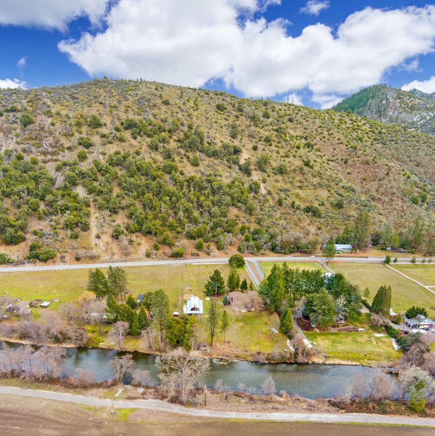 Relax on the River, located near wineries & just a few miles from Applegate Lake. This wonderful property offers a beautiful 2837 sq ft home on 2.98 acres of flat land along the Applegate River. The spacious SINGLE LEVEL HOME features 3 bedrooms each w/a private bath, + a separate office w/ beautiful wood & leaded glass doors. The Primary Master is spacious w/2 walk-in closets, water closet, tile shower & separate tub. The lg kitchen is appointed w/granite counters, dbl ovens, 6 burner stainless cooktop, wine refig, a lg. island, & beautiful wood cabinetry. The kitchen is open to a spacious living area w/views & access to a lg patio, beautifully manicured yard, mature trees & the river. Additional home features incl. formal dining, custom wood doors, high ceilings, wood beams, built-in cabinetry, wet bar, 2 wood stoves, propane stove, 4th full bath, laundry rm, 2 car garage, vinyl fencing, fenced garden area, 1232 sq ft barn/shop, & a 16x19 pavilion near the river's edge.