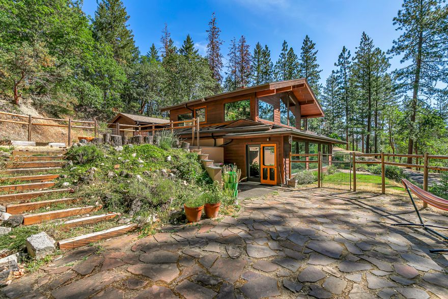 Peaceful Mountain Retreat Just Minutes from Town! This handcrafted Northwest home is a private sanctuary nestled behind a gated drive, offering stunning views, abundant natural light, and timeless artistic details throughout. Picture windows, skylights, and warm wood finishes (redwood, hemlock, oak) create a spacious, light-filled interior.  
The primary suite features a spa-like Corian shower, while the custom kitchen includes Corian and tile surfaces, wood cabinetry, and a certified wood stove in the living space. A separate space in a newly built Geometric Dome - for guests, office space, yoga, the possibilities are endless! Enjoy beautiful gardens, a detached garage, attic storage, and a fenced area for pets. Hiking trails are just minutes away, with downtown Ashland, Shop'n Kart, and the YMCA all within a short drive. Well cared for and full of character, this mountain oasis offers both serenity and convenience—a lifestyle you'll feel the moment you arrive.