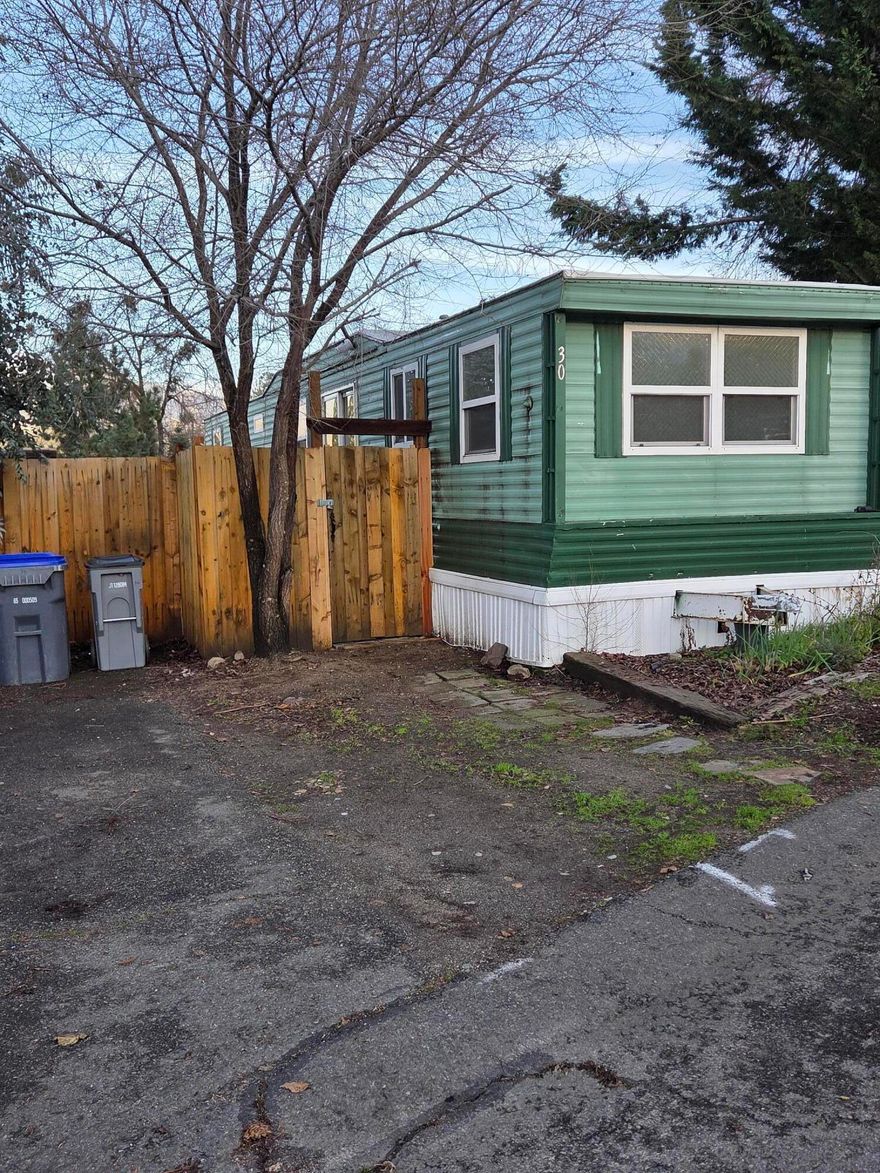 Tucked away at the back of Siskiyou Village Mobil/RV Park which is an ''All-AGE'' park with a great rural feeling that offers amazing mountain views. This cozy single wide mobile home features two decks for entry into the home and updated fencing around the lot that adds so much privacy and is ready for you to add landscaping for you and your pet(s) Pet(s) on Park Approval). Per past owner the vinyl windows and roof were updated in the past, by Access. The plumbing lines underneath the bathroom area were replaced by Huskill's Plumbing in 2022. Inside the home the living room is open to the kitchen with an area of new flooring, a gas range and elect.refrigerator and the bathroom features a tub/shower combo. There is an enclosed bonus room at front of home that could serve as an office/dining room. The Park offers a low-cost laundry on site and a dog walking area.Park Space Rent will be $770./mo. with w/s/t included To be Sold ''As-Is'' and ready for your own personal ideas and touches