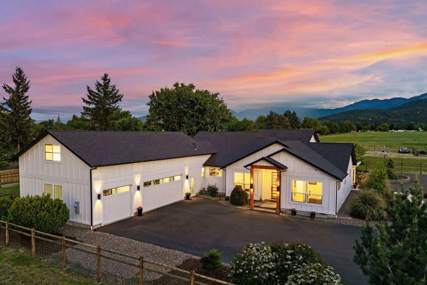 Stunning 2,979 sq ft home on 1.95 beautifully landscaped acres with sweeping views from Mt. Ashland to the Table Rocks. Light-filled and thoughtfully designed, the open floor plan is perfect for entertaining. The chef's kitchen features a large concrete island, custom cabinetry, gas range with double ovens, full-size fridge and freezer, and a spacious butler's pantry. The great room offers a modern fireplace and expansive windows framing the mountain views. The split floor plan includes 4 bedrooms, 2.5 baths, and a luxurious primary suite with walk-in shower, double vanity, and his-and-hers walk-in closets. Upstairs includes a finished attic space with endless potential, plus bonus room.  An oversized 3-car garage provides ample room for cars or workshop space while the gated paved driveway provides piece of mind. . TID irrigation keeps things green, and a 40 GPM artesian well secures water availability, ideal for a mini farm lifestyle—all just minutes from town!