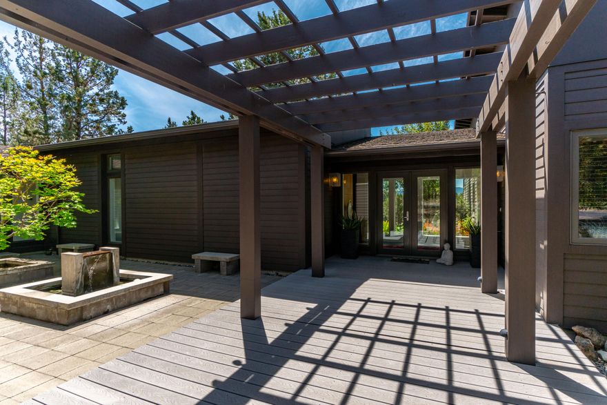 Anchored in classic design principles with a nod to Mid-century architecture, this timeless gem is a retreat in the community of Tumalo. Situated on 5 private acres, this home offers a peaceful escape from the everyday rush but is just minutes from the amenities of Bend. Inside, expansive floor to ceiling windows bathe the great room in natural light, overlooking open land & Cascade mountains. The open concept living area is spacious and flows seamlessly to the outdoors. Take your pick of an expansive west facing deck or a tranquil interior courtyard with mature maples and water feature. The distinctive primary suite includes a gas fireplace, access to the deck & hot tub and abundant custom storage. Two guest bedrooms & separate office/flex space complete the single level floor plan. Custom maple cabinetry is featured throughout the home offering abundant storage in style. Additional perks include an oversized 3 car garage, covered RV parking & charming fenced garden with greenhouse.