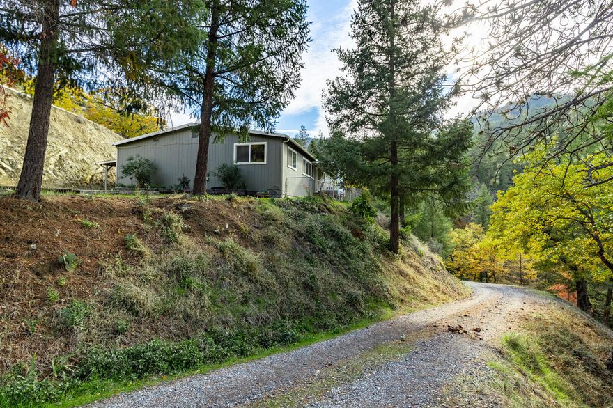 Private knoll-top setting with wonderful mountain views and abundant Evergreens. Set well back off the road, this spacious home offers an open floor with vaulted ceilings, laminate floors, all thermo windows and newer certified woodstove on brick hearth. The light and bright kitchen features wood cabinetry, built-in microwave, glass top range and breakfast nook. The master wing offers an oversized walk-in closet and spacious bath with abundant storage and tile floor. This home features a total of 4-bedrooms and 2-full baths with indoor utilities and covered hot tub off of the front deck. 2-car detached garage, carport, grid-tied solar power, RV parking and above ground pool with extensive decking and pool house. Good well per owner with newer well pump and 2000 gallon holding tank, this property is located just minutes to the Applegate River, Applegate Lake, some of Oregon's finest wineries and it is adjacent to Government land! Great privacy and loaded with potential.