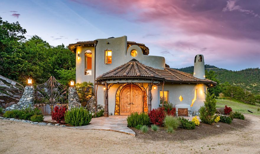 Centrally located between San Francisco and Portland, just minutes from I-5, 700 awe-inspiring acres of oak savannas and rolling meadows gently rise, until your view of the Siskiyou mountains feels so close, you might reach out and touch it. Sitting on a high bench, a spectacular 8,880 sq. ft home exalts the grandeur of nature that surrounds it. With its graceful, curvaceous design, myriad of windows, and unique features like rounded corners and sculptural appointments in copper, glass, stone, granite, local and exotic wood, this breathtaking home is beyond custom; it is a work of art. Every direction offers an unparalleled view. This astonishing property enjoys a pool, an outdoor entertainment space, an off-grid cabin, and features a 3000 sq. ft. basement level ready to be transformed by your imagination. Offering magnificent sanctuary and adventure, as well as convenience, the surrounding region of Southern Oregon is known for wine and phenomenal outdoor recreation opportunities.