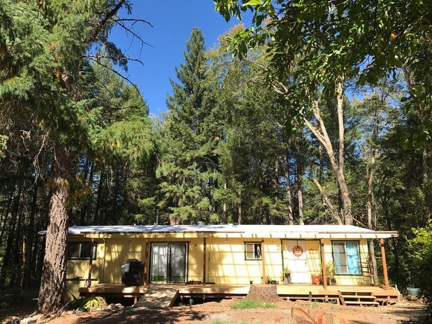 This home is set back off the road for privacy & offers a seasonal creek & ample space for outdoor living. Certified Wildlife Habitat by the National Wildlife Federation in 2017, fostering a haven for birds and pollinators. Mature fruit trees including Granny Smith apples, Bing cherries, Japanese plums, & Thundercloud plums, alongside established herb gardens & vibrant perennial flowers. Two wells on the property, one producing 20 GPM & the 2nd currently not in use is 4 GPM (per seller). The home was updated in 2017 with the following: 30-year roof, 48x12 covered front deck with stairs and ramp for easy access,  primary bathroom updated with new vanity, tub/shower, faucets, toilet, subfloor and LVP flooring.
*Detached garage/shop with 220V, plenty of room for your toys and RV. Front of property has 7 ft fencing. Possible financing. Buyer to perform their own due diligence into all aspects of the property with the appropriate agencies for condition, permits, zoning & intended uses.