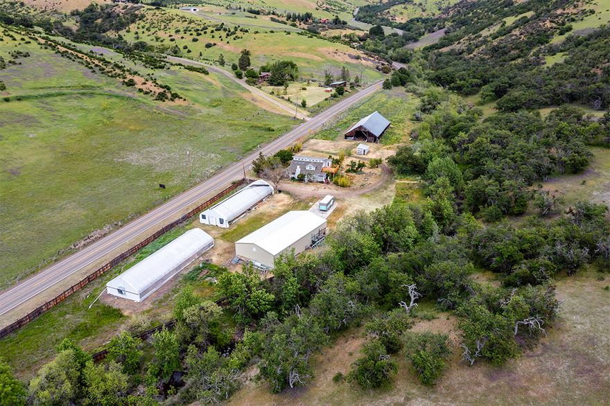 Priced to Sell, As Is!! 26+ acre EFU-zoned property offering peace, privacy, and incredible potential, just 7 miles from Ashland's celebrated theaters, fine dining, and iconic Lithia Park. A 1940 farmhouse blends timeless charm with thoughtful updates: warm bamboo floors, abundant windows, and inviting natural light. Enjoy an open living/dining area with wood stove, spacious kitchen with dining bar and breakfast nook, plus 3 bedrooms, 2 baths, and a loft retreat. The upstairs primary suite opens to a large deck—perfect for sunsets, stargazing, and quiet mornings. Relax in the cedar sauna after a long day. Outside, you'll find a 40x80 insulated shop with concrete floor, two 30x95 greenhouses with raised organic beds, and a historic late-1800s barn. Fenced pastures, garden areas, and a seasonal creek complete this inspiring setting. Whether you envision a working homestead, lush gardens, or your personal sanctuary, this special property is ready for its next chapter.