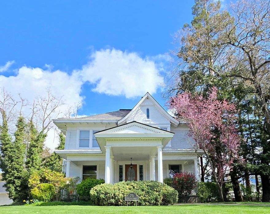 Built in 1905, this stunning Colonial on the Grants Pass historic registry blends timeless charm with modern allure, just steps from downtown. Spanning 3,412 sf, this 5-bed, 2.5-bath home sits on a .40-acre lot with striking curb appeal. A grand portico entry with stately columns and a front sitting porch welcomes you into a foyer adorned with crown molding, tall ceilings, and intricate woodwork. The formal dining room flows into a spacious kitchen with a butler's pantry, while the great room and living room share the warmth of an original wood-burning fireplace. Hardwood floors, solid doors, and stained-glass windows elevate its historic character. The upstairs primary suite offers a sitting area and en-suite bath. A den, sunroom, and enclosed porch add versatility. A 1,408-sf basement (not in main sf), 3-car carport, workshop, and large deck overlooking mature landscaping and a lush green lawn contribute to this a rare historic treasure.