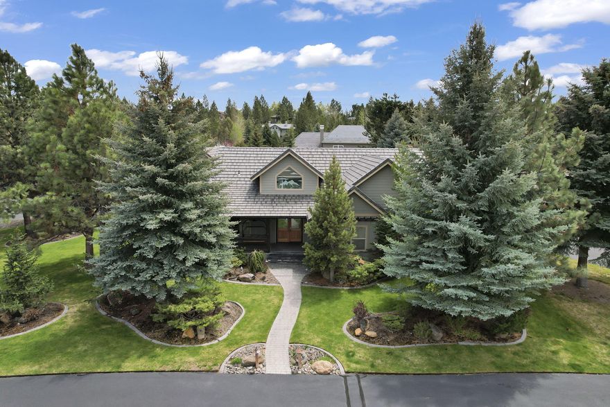A dream NW style home on Bend's westside with a park -like setting on .42 acres. This single story great room home has vaulted ceilings throughout the home. The extra large primary suite features a tile shower, dual vanity & deep soaker tub. The kitchen features a large 5-burner Dacor gas grill, granite countertops, black appliances & a built-in dining table looking out to the back courtyard-full outdoor kitchen, firepit, hot tub and covered deck for dining outdoors. Inside the single story home are two guest bedrooms and the second bathroom all on beautiful pine flooring. The 3-car epoxy floor heated garage is off the main house with a large work bench, shop and an upstairs living area which would be ideal for a bedroom suite, media room, or  guest with its own full bathroom.