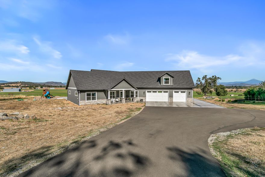 An absolute treasure on Old Stage Rd, truly 1 of a kind & a must tour. Nothing like it on the market today. 1 owner custom 2020 built home w/gated entry, privacy, 3 irrigated acres w/irrigation rights, high producing well (per owner), fenced & cross fenced, & beautiful views of green fields, Table Rocks & Mt. McLoughlin. Single-level design w/bonus theater & 1/2 bth upstairs, vaulted ceilings, wide hallways, & too many upgrades & extras to list. Gourmet kitchen has granite island, custom cabinets, KitchenAid SS appliances, gas cooktop, wine fridge, & kitchen pantry. Spacious primary suite offers dual walk-in closets w/built-ins, custom wood feature wall, soaking tub, walk-in shower, granite counters, & private views. Split bedroom floorplan includes Jack & Jill bedroom, 4 bedrooms, 1 office, & multiple baths. Oversized 3-car insulated garage w/220 power, xtra storage & RV parking. Back yard features covered stamped patio, extensive concrete, play structure & incredible panoramic views