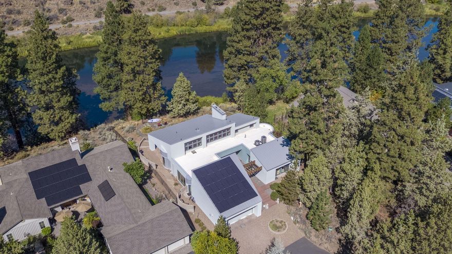 Where the river bends, so does chic living. This Bend home offers 100 feet of Deschutes River frontage just seven minutes from downtown. Thousands spent on upgrades, roofing, siding, windows, HVAC, paint, and fixtures make it move-in ready and timeless. Soaring ceilings and celestial windows flood the living spaces with light, while wood floors, slate tile, and rich fir trim balance mid-century warmth with contemporary flair. The kitchen shines with a stainless-steel island, complemented by family, office, and mudroom spaces. The primary suite offers riverfront patio access, fireplace, built-in audio, spa-worthy bath, and a grand closet with Euro-style laundry. Two additional bedrooms and a full bath complete the plan. Outside, a flagstone path leads to the water's edge, perfect for paddleboarding or floating the river. A true 2-car garage houses solar power (no electric bill), EV charging, and smart storage. Seller is motivated—don't miss this rare opportunity on the Deschutes!