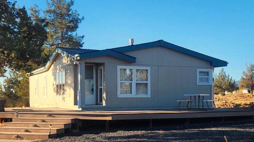 Great opportunity to own 5 acres in 3 Rivers, move-in ready, fabulous rim views of the Cascades, Smith Rock, and Big Canyon. 2 generous bedrooms, 2 full baths, open concept w/great room, kitchen & dining w/tons of built-in storage plus propane fireplace (rented tank) for heating. Laundry room with additional man door  leading to large wrap-around deck for entertaining and relaxing with friends and family.  All appliances and furnishings included at no stated value. Solar owned system includes 500 watts of PV panels, inverter/charge controller and new batteries in 2025. 1200 gallon cistern in separate-insulated building, outhouse, storage building and mechanical building plus new 30 year roof installed recently. This one won't last long with all these features and an affordable price. Call your favorite agent to book a viewing today.