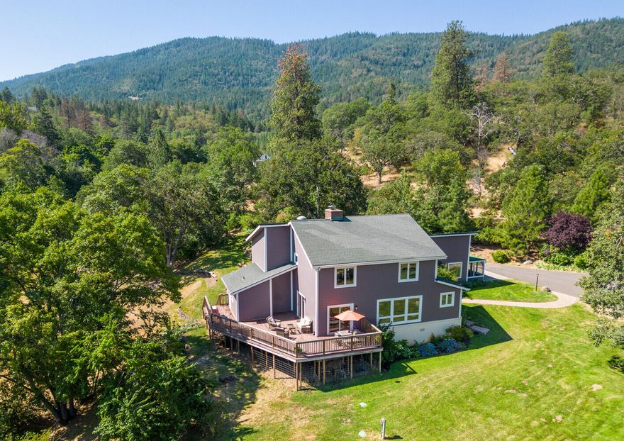 Private & magical, this rural gem, adorned by majestic oaks, rich fertile irrigated land & a panorama of the Siskiyou & Cascade Ranges will call you home. The fully usable acreage is open, sunny & pastoral w/a creek-side setting, shade & fruit trees & a bountiful deer-fenced garden. Excellent 25 GPM well. The home is inviting, large & comfortable w/vaulted ceilings & walls of windows that feature a beautiful landscape in all directions. Spacious interior w/large main living areas, an open & bright kitchen w/oversized island & dining bar, + tons of counter space for multiple chefs. Complementing the living spaces are a family/library room, a restful sunroom overlooking the gardens, & a private home office. Outdoor decking & enclosed porches expand the space. Spacious attached full apartment offers extra living & gives many options for extended family or guests. Special detached modern office w/half bath for remote work, barn, garage with shop & a barrel sauna.