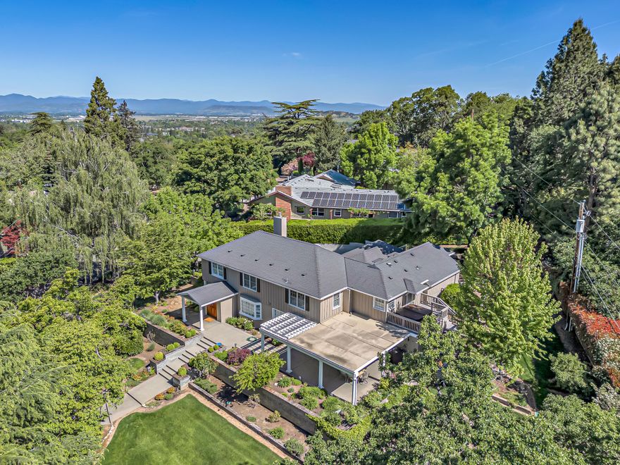 Nestled on nearly half an acre of stunning, park-like grounds with mature trees and lush landscaping. This beautiful historical East Medford home offers privacy in an ideal location near the Rogue Valley Country Club, medical facilities, and local wineries. The warm, inviting remodeled kitchen shines with stainless steel appliances and effortless flow. The two spacious primary suites each feature abundant natural light, an office, updated bathrooms, walk-in closets, gorgeous travertine.  Endless charm and custom details make this home one of a kind. A 256 sq ft ADU studio apt. w/ kitchenette & full bath adds exceptional versatility—perfect for guests, extended family, or potential rental income. Additional highlights include a well-appointed laundry room with ample storage, 3 bay garage w/ workshop, and ample parking. Meticulously cared for and privately situated, this home offers a rare combination of tranquility, functionality, and proximity to everything East Medford has to offer.