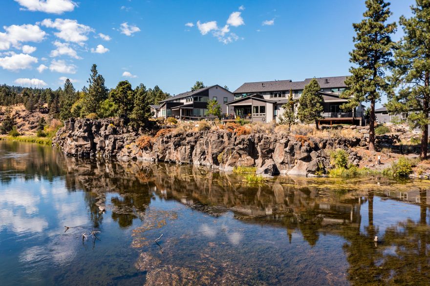 Nestled on a premium lot overlooking the Deschutes River, this stunning townhome offers exclusive river access for kayaking or paddleboarding steps from its back door. Enjoy a bright interior with contemporary finishes, engineered hardwood floors, smart home features, and river views from nearly every room. Boasting soaring ceilings and a modern fireplace, the 2-story, sun-drenched great room flows into a gourmet kitchen with quartz countertops, stainless appliances, and a large island with wine fridge. The main-level primary suite pairs southeastern river views with tray ceilings, blackout blinds, a walk-in closet, deck access, and a spa-like bathroom featuring a deep soaking tub and dual vanities. Additional spaces include a home office, laundry room, guest suite with full bath, and loft with a wet bar and wine fridge. Outdoor living is redefined on the covered deck, where a hot tub and built-in gas firepit promise year-round enjoyment against the ever-changing backdrop of the river