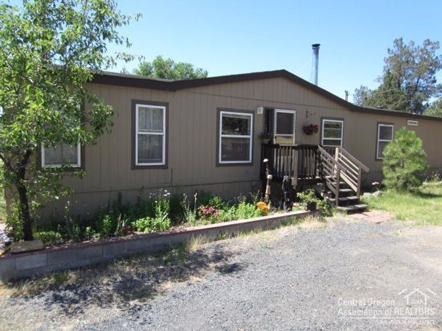 This quaint 1.06 acre property with mountain views and irrigation, is perfectly situated between Bend and Redmond. This Manufactured home has a great room layout; 3 bdrm, 2 bath PLUS bonus rm. The family rm has a newer wood burning stove, for comfy winters. An outbuilding that can be used for workshop or storage with attached greenhouse and a large garden area.