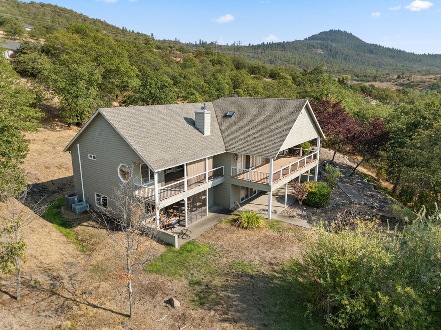 Welcome to your private 9.9-acre retreat with sweeping mountain and city light views! This beautiful 4-bedroom, 3-bath home offers warmth and comfort at every turn. Hand-scraped engineered hickory floors, a spacious kitchen with island and under-counter lighting, and a cozy family room with wet bar set the stage for everyday living and memorable gatherings. The inviting primary suite provides a peaceful escape with serene views and a generous walk-in closet. Enjoy year-round comfort with ceiling fans, a wood-burning fireplace, and a woodstove. Step outside to a huge covered composite deck—perfect for morning coffee, sunset dinners, and soaking in the beauty of nature. With a 3-car garage and room for your RV, boat, and toys, this property offers space, privacy, and endless opportunities to live the lifestyle you've been dreaming of.